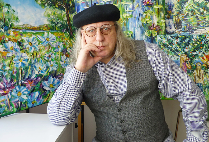 Der Künstler Mirek Kuzniar steht vor einem seiner Bilder